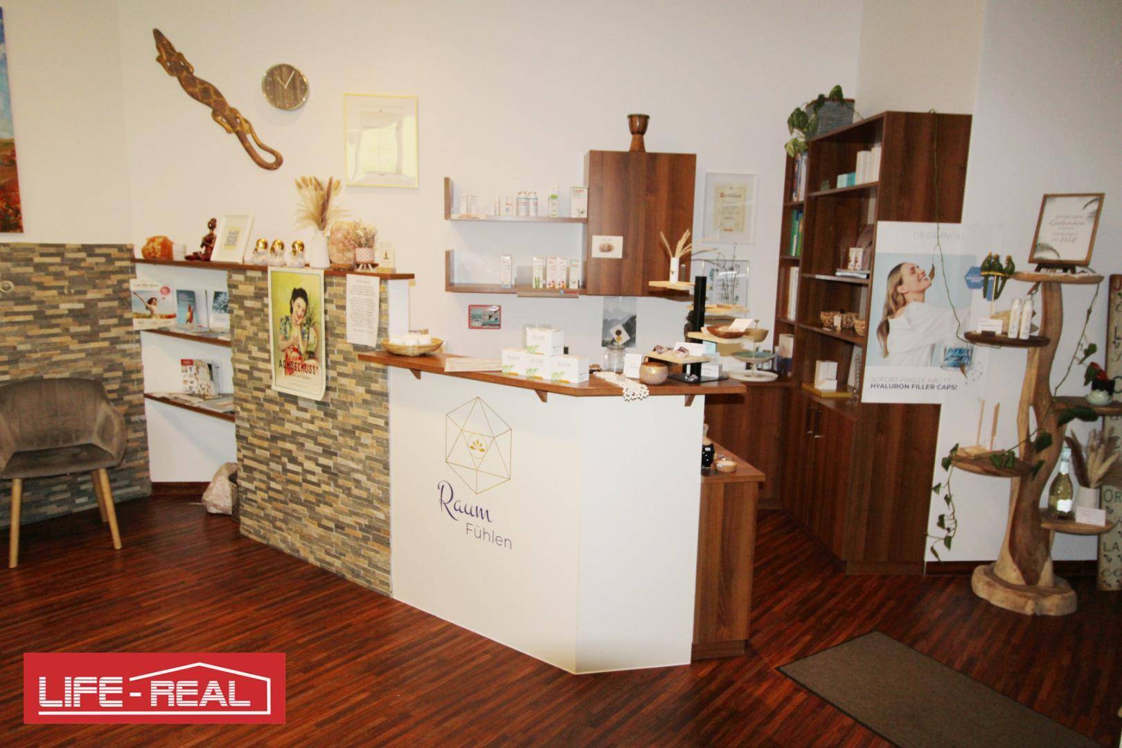 Detailansicht des Empfangsbereichs mit einer Rezeptionstheke, Holzregalen und einer dekorativen Steinwand.