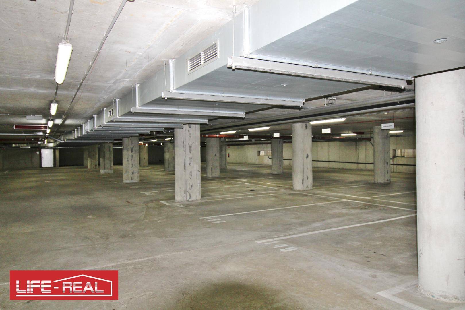 Weitläufige Tiefgarage mit vielen Parkplätzen und sichtbaren Säulen, bietet sichere Abstellmöglichkeiten.