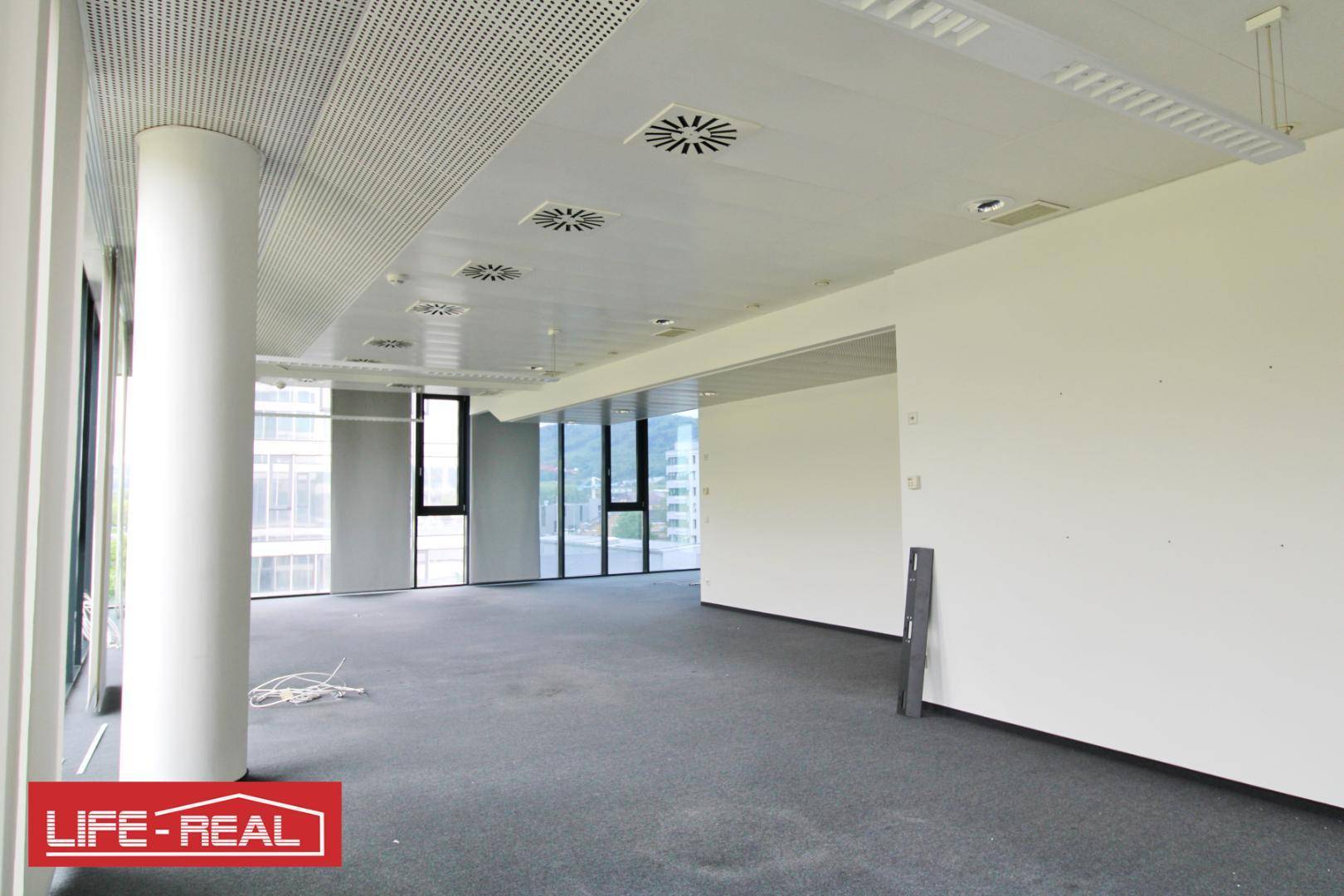 Großes, leeres Büro mit Teppichboden und weißen Wänden, bereit für die individuelle Gestaltung der Arbeitsbereiche.