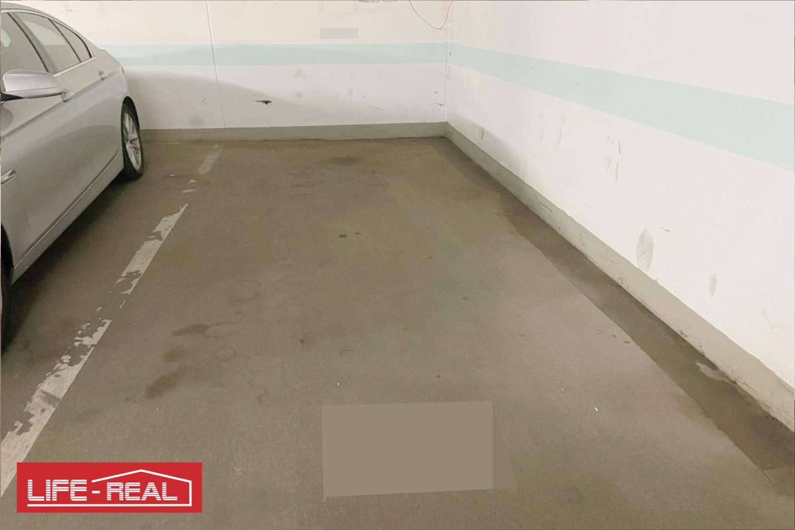 Tiefgaragenstellplatz mit einem geparkten Auto und klaren Markierungen auf dem Betonboden.
