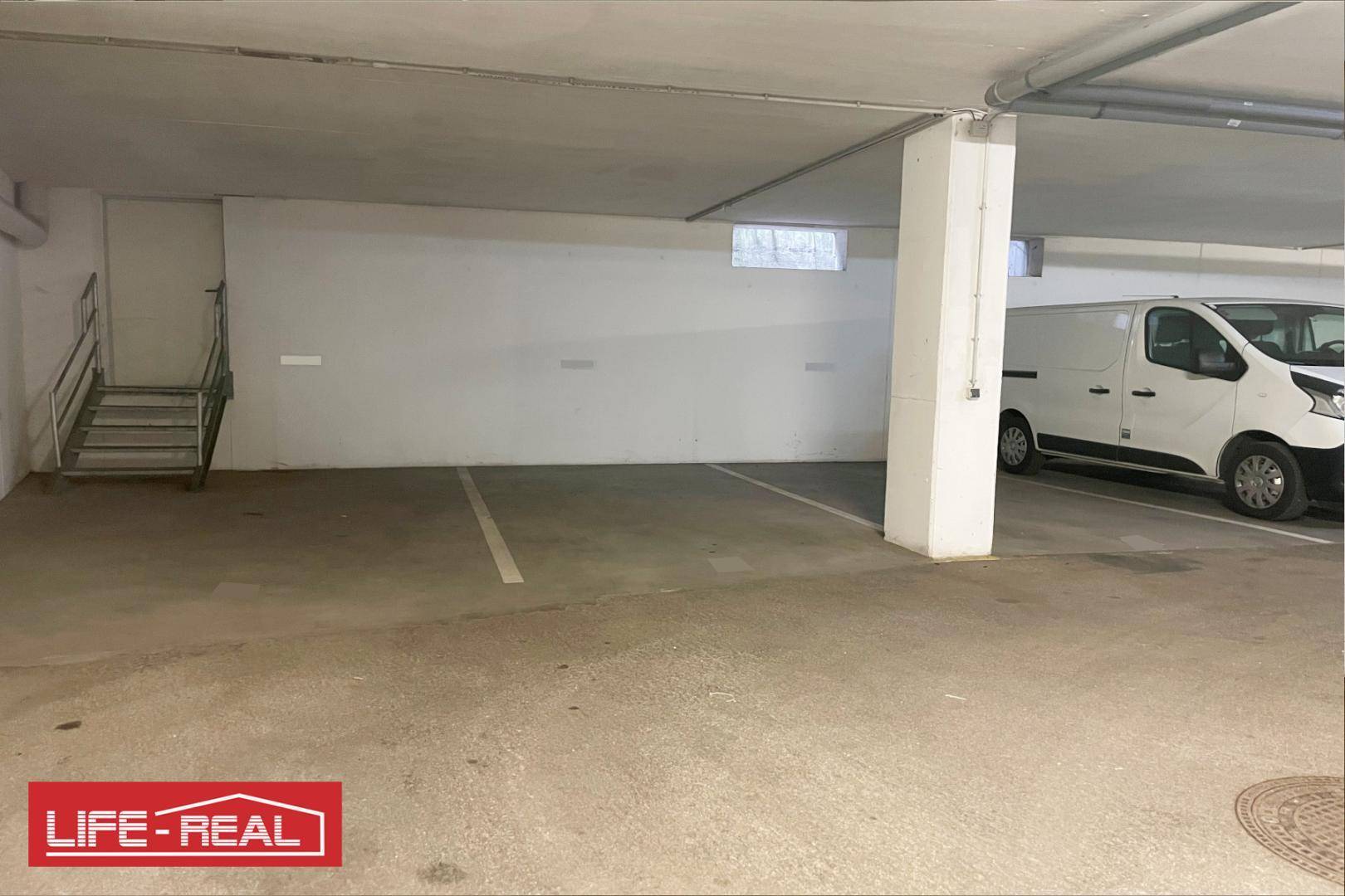 Tiefgaragenstellplatz mit Zugang zu einer Treppe und einem geparkten Lieferwagen.
