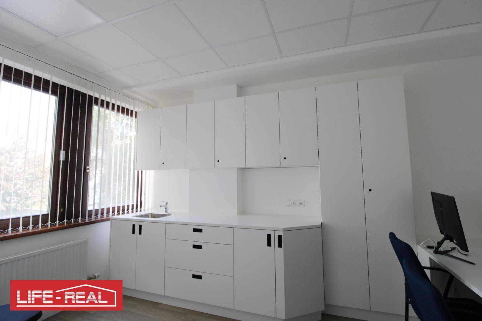 Funktionale Küchenzeile mit weißen Schränken, Spüle und Arbeitsplatz in einem hellen Raum mit Fenster.