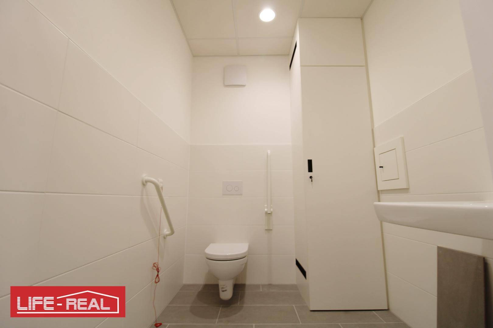Barrierefreie Toilette mit Haltegriffen, Wand-WC und modernen Fliesen, sehr sauber.
