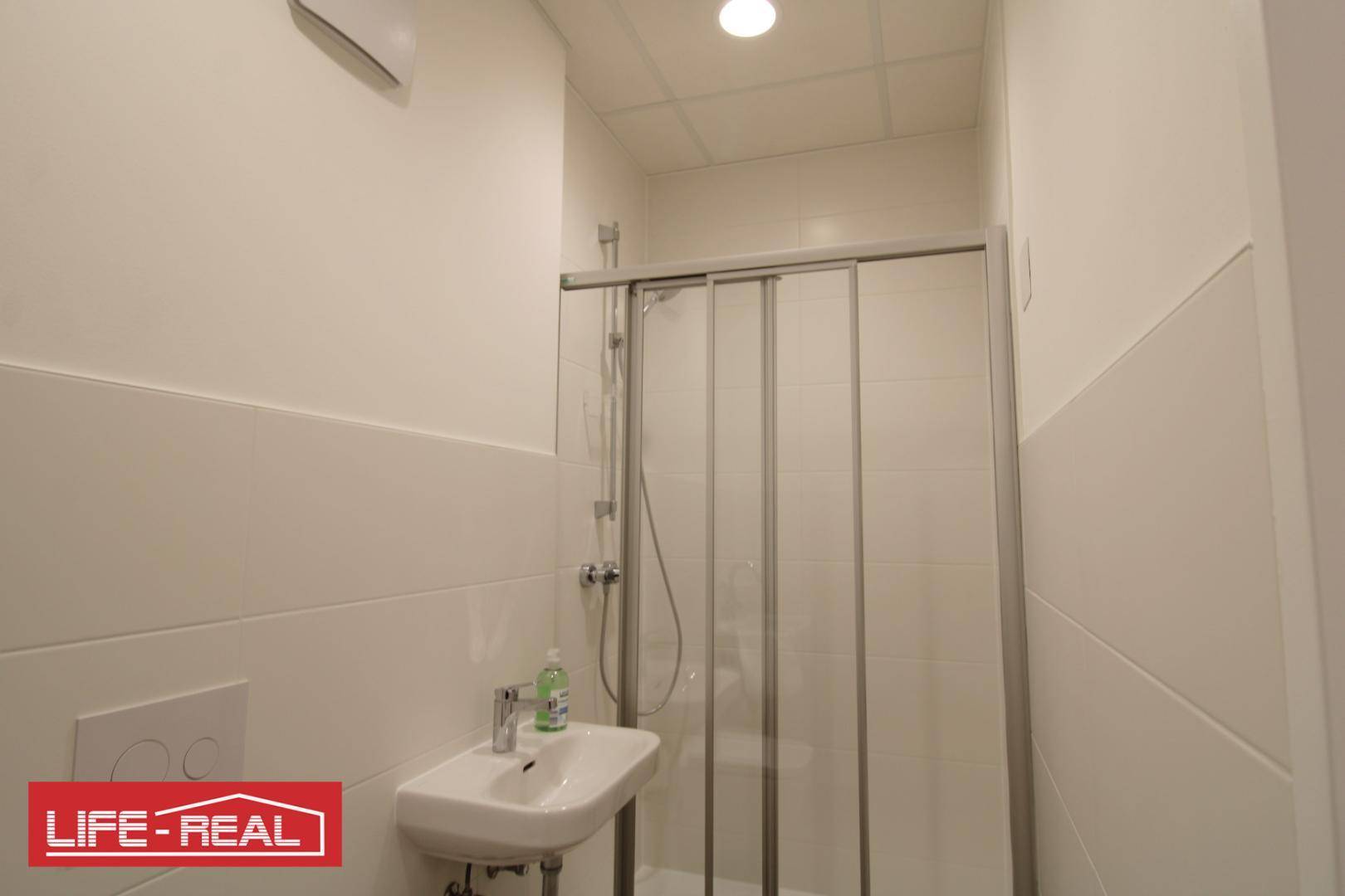 Modernes Badezimmer mit Duschkabine, Waschbecken und hellen Fliesen, sehr gepflegt.