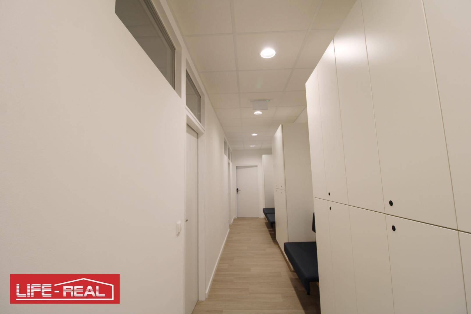 Heller, langer Flur mit Schließfächern und Sitzgelegenheiten, der zu weiteren Räumen führt.