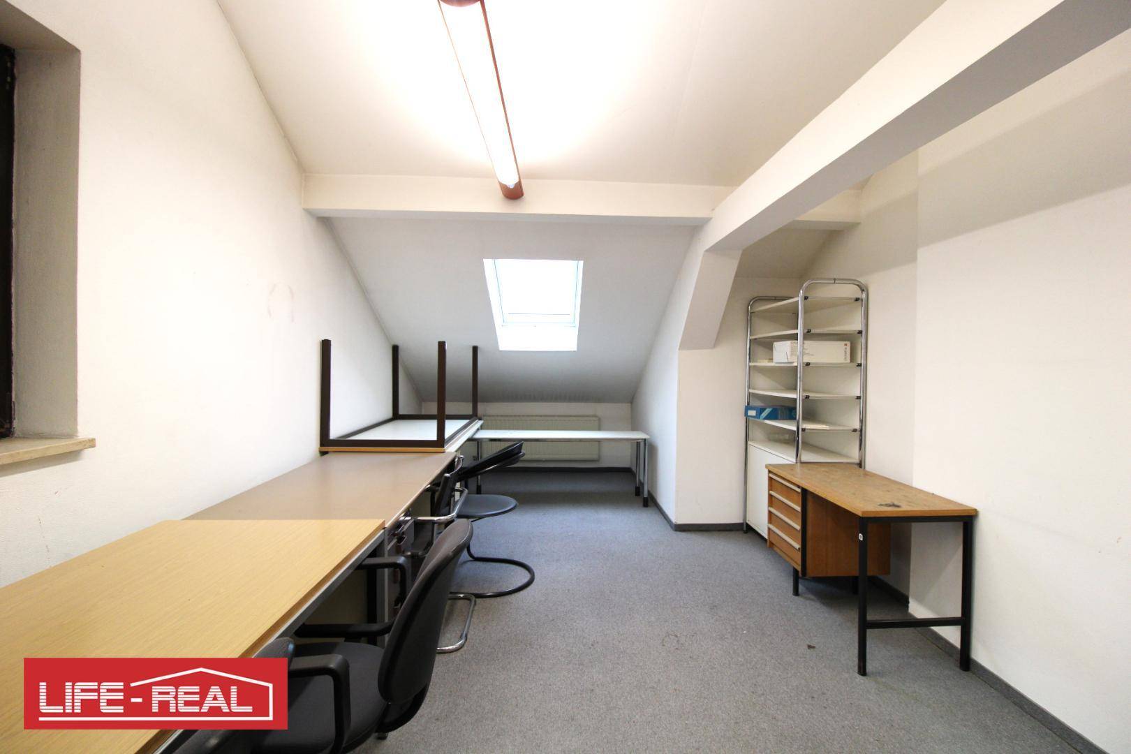 Langer Büroraum im Dachgeschoss mit mehreren Schreibtischen entlang der Wand und einem Dachfenster.