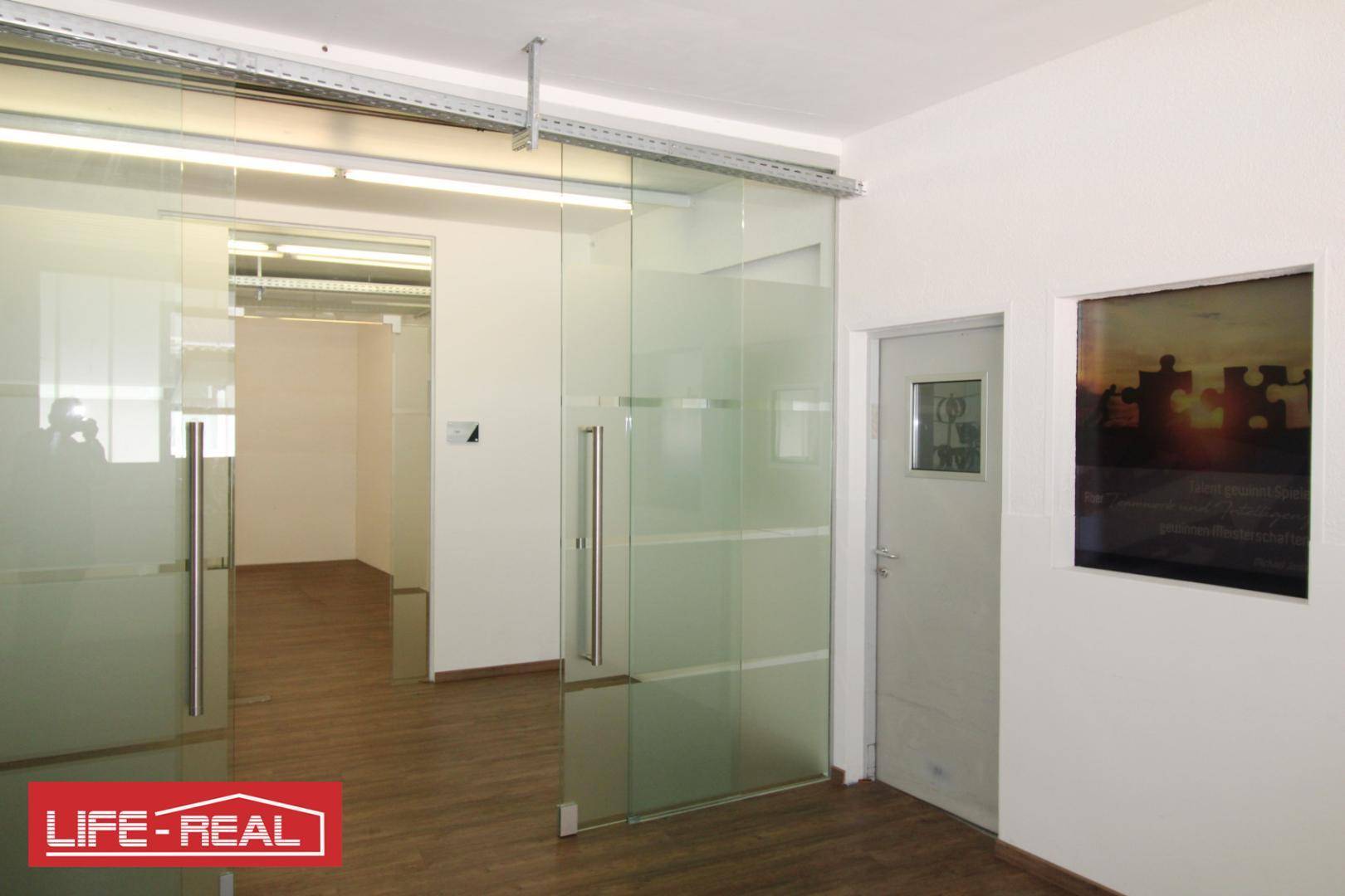 Innenansicht eines Büros mit Milchglas-Schiebetüren und Blick auf ein Fenster im Nebenraum.