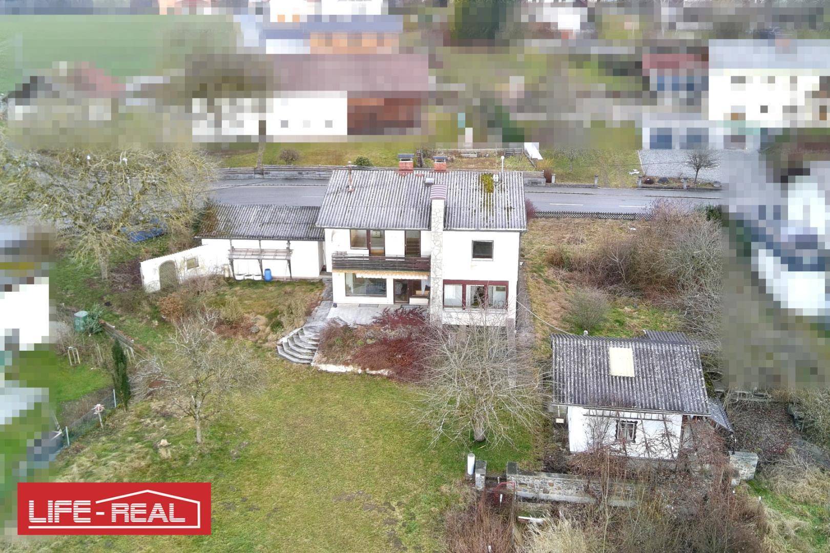 Luftaufnahme eines Hauses mit Garten, Nebengebäuden und umliegender ländlicher Bebauung.