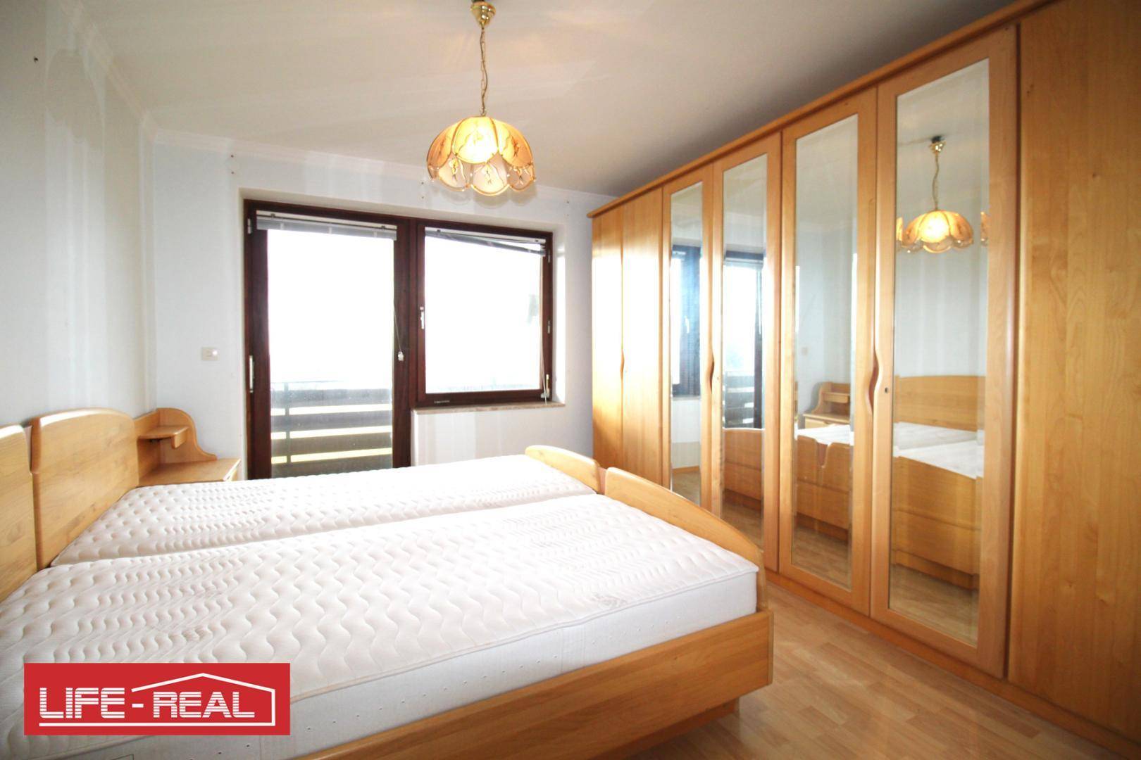 Schlafzimmer mit zwei Einzelbetten, großem Spiegelschrank und Fenster mit viel Tageslicht.