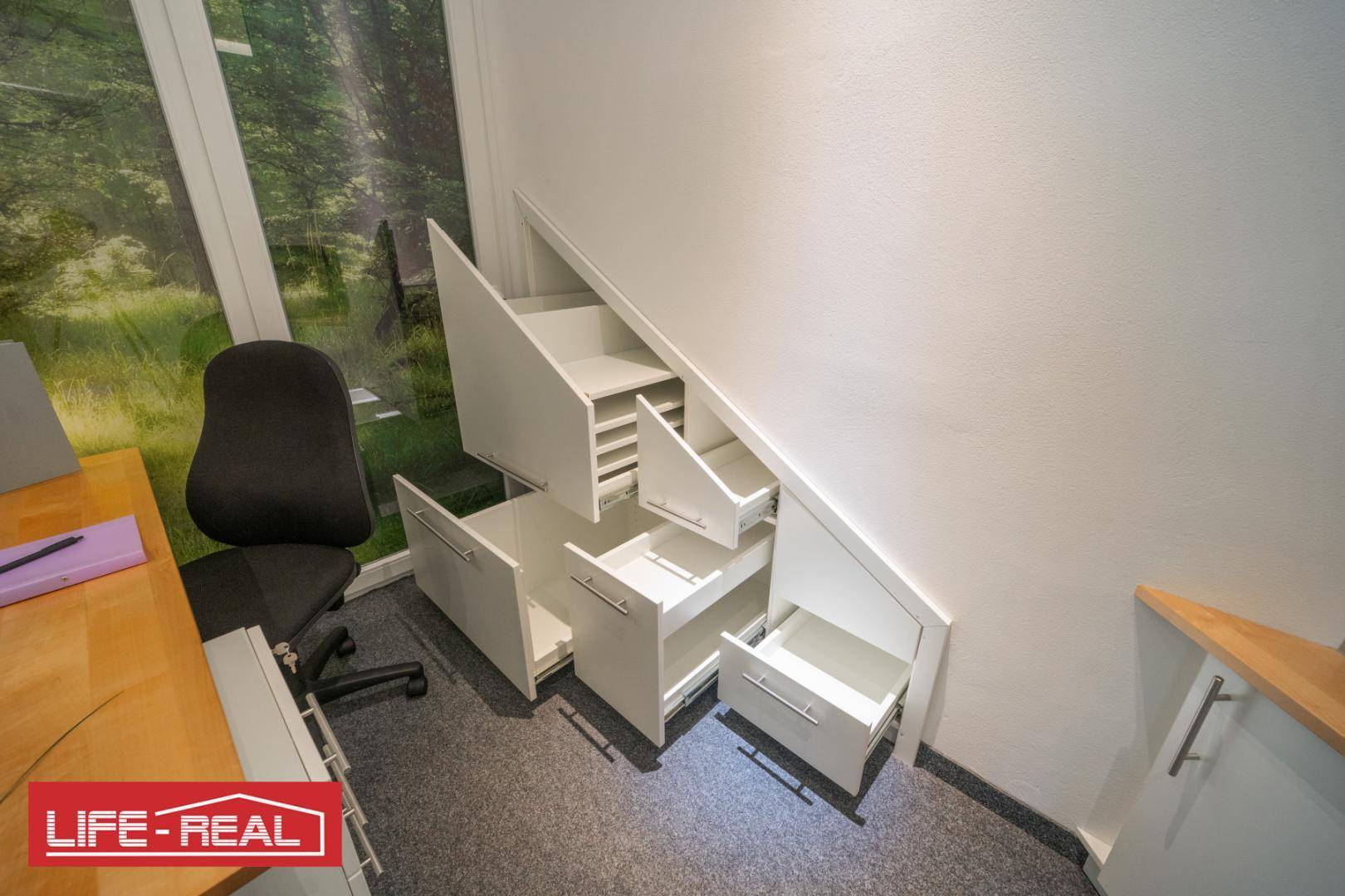 Clever genutzter Stauraum unter der Treppe mit mehreren ausziehbaren Schubladen und integrierten Fächern.