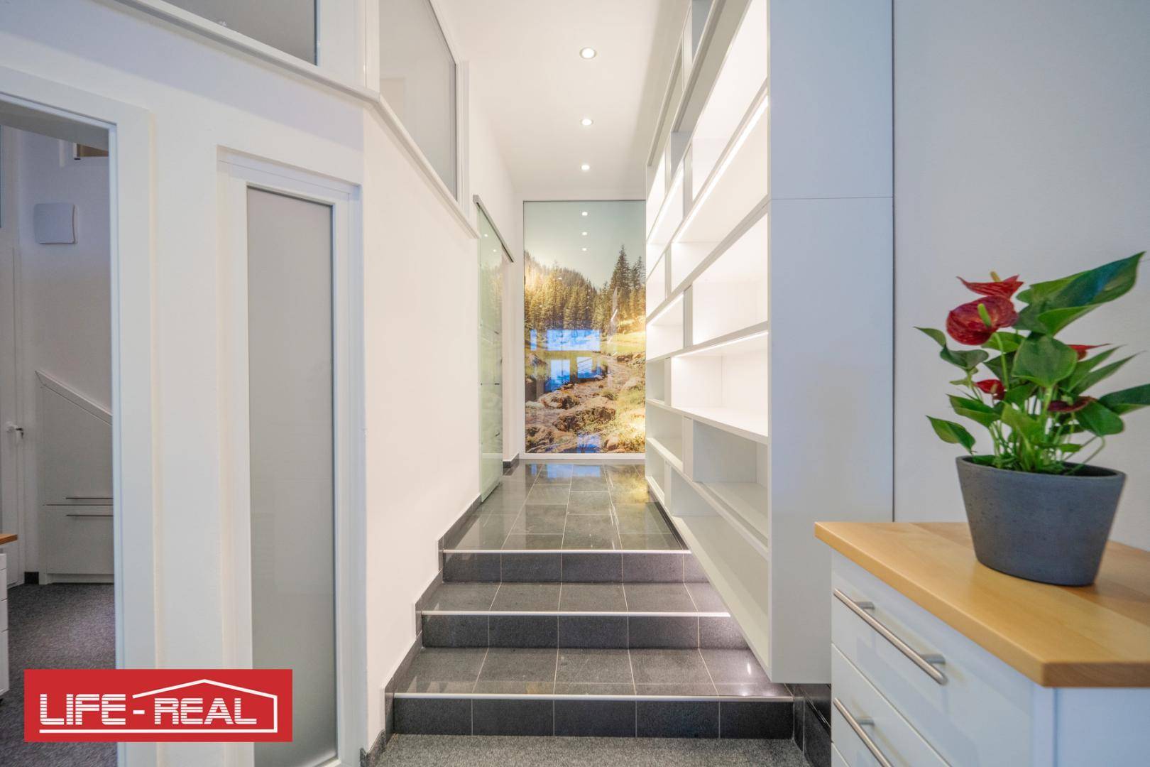 Heller Flur mit Fliesenboden, Regalen und einer Wanddekoration mit Berglandschaft, einladend und modern.