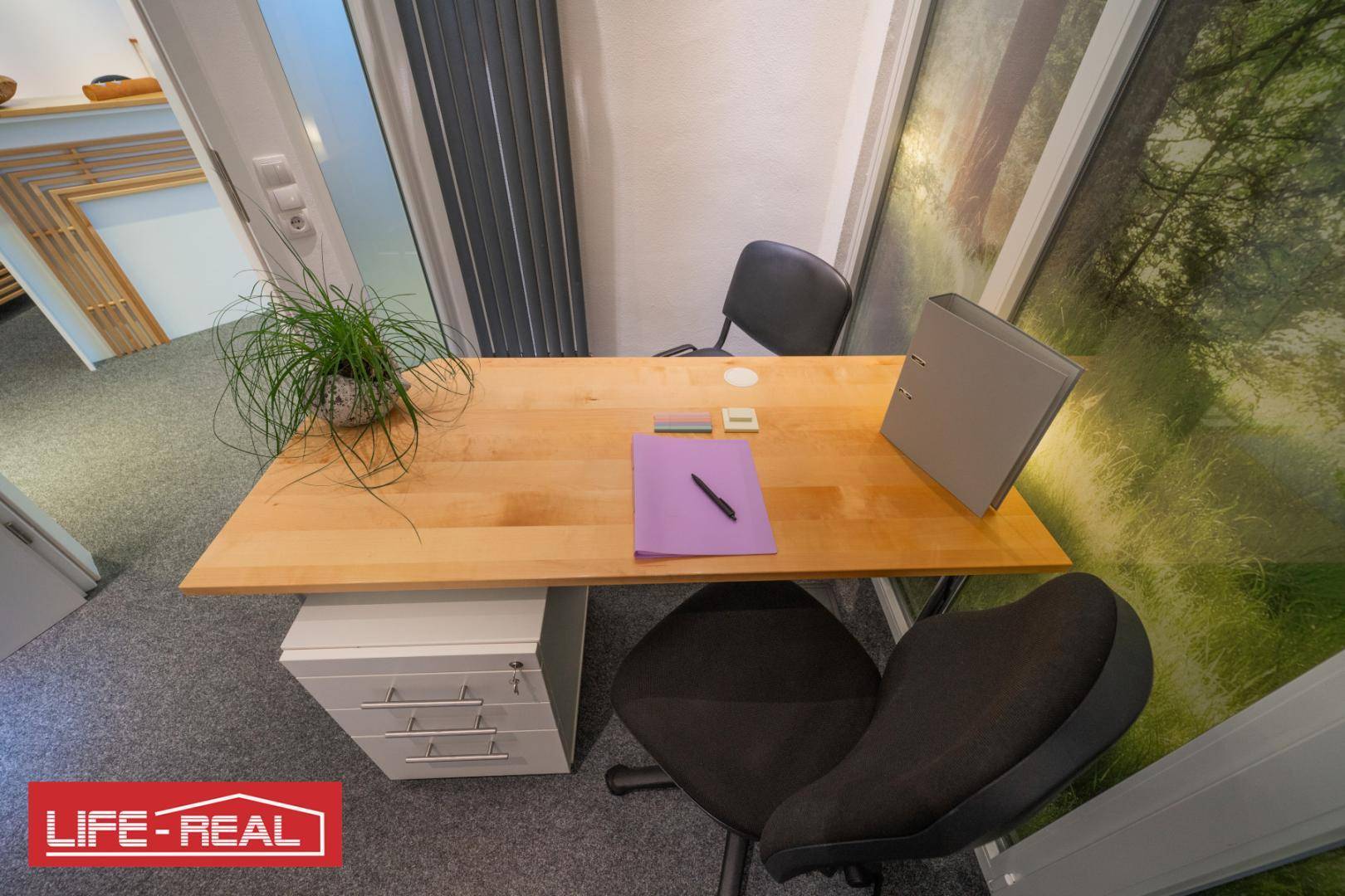 Arbeitsplatz mit Holztisch, Bürostuhl und einem Fenster mit Waldmotiv-Folie für Privatsphäre und Atmosphäre.