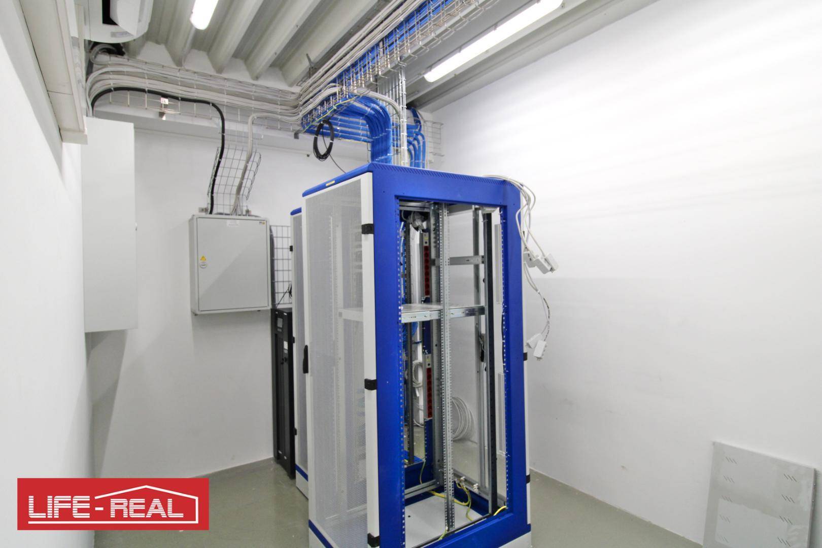 Serverraum mit blauen Kabelkanälen, einem Serverschrank und Klimaanlage an der Decke.