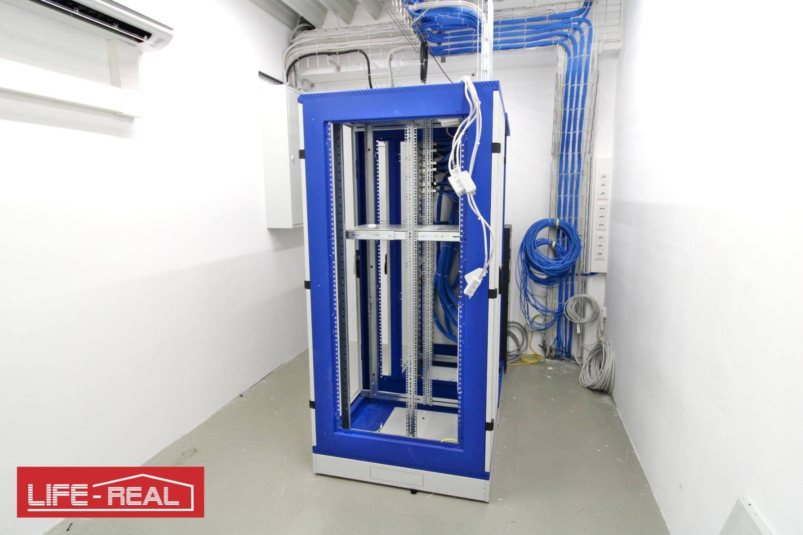 Serverraum mit blauen Kabelkanälen, einem Serverschrank und Klimaanlage an der Decke.
