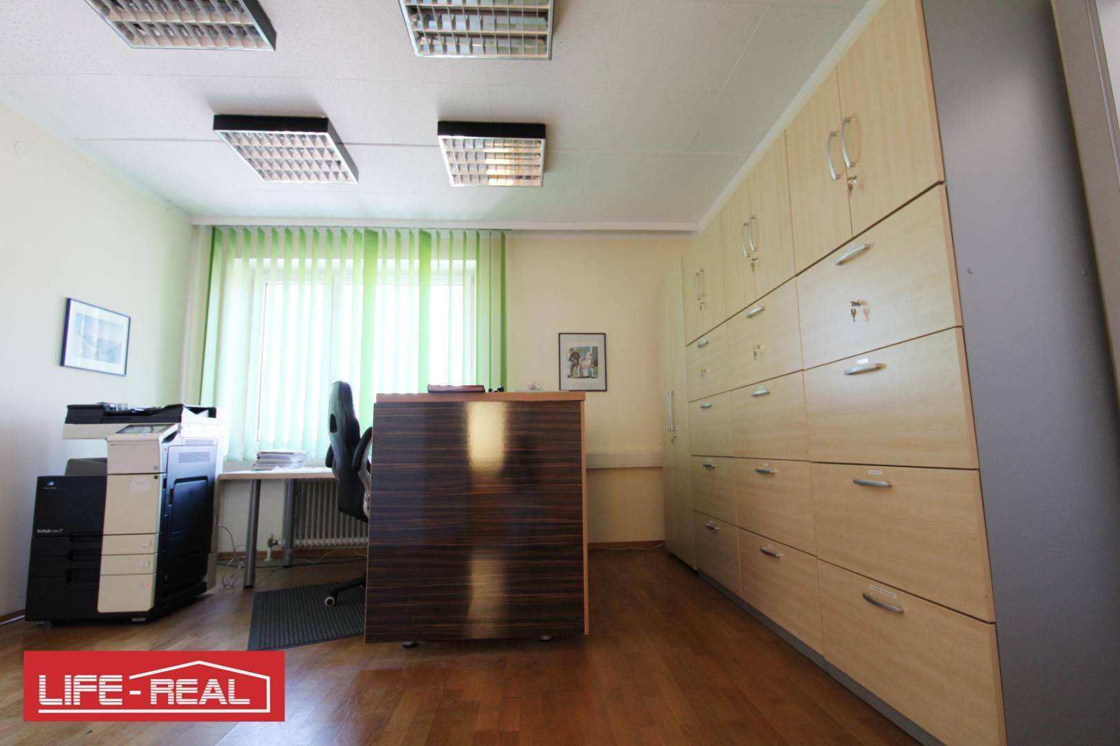 Büro mit Einbauschränken, einem Kopierer und einem Schreibtisch mit Bürostuhl.