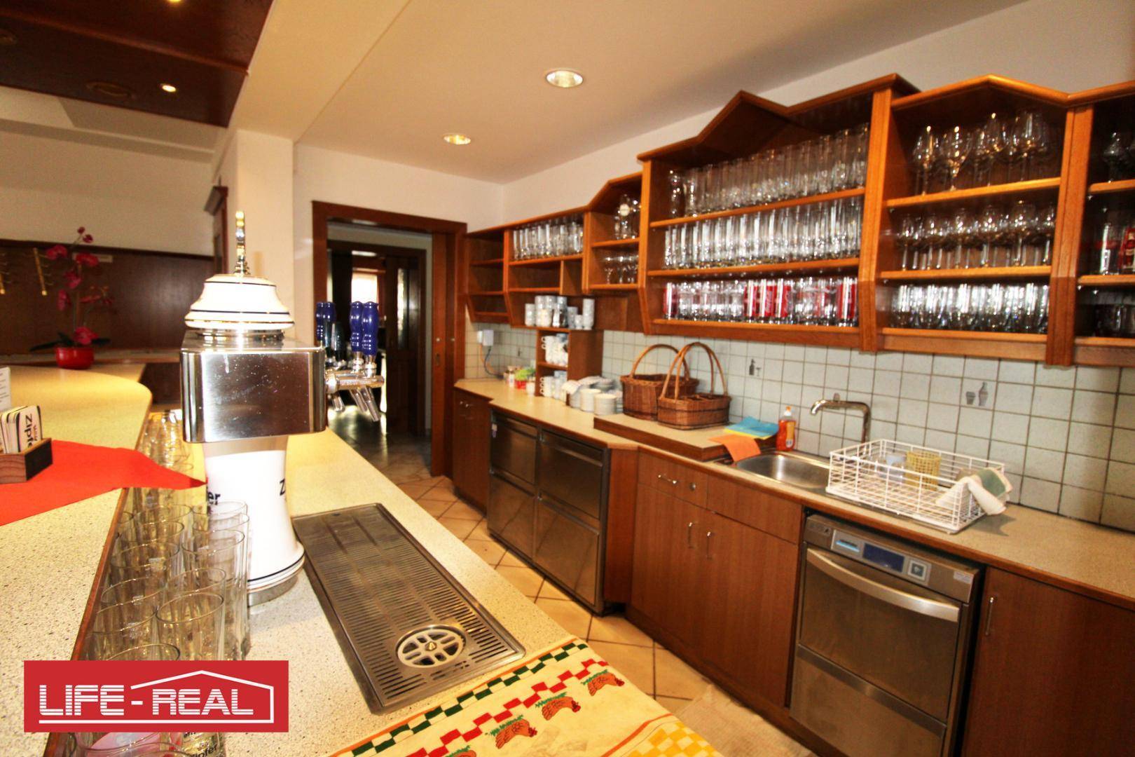 Detailansicht einer Bar mit Zapfanlage, Spülbecken und Regalen voller Gläser, bereit für den Service.