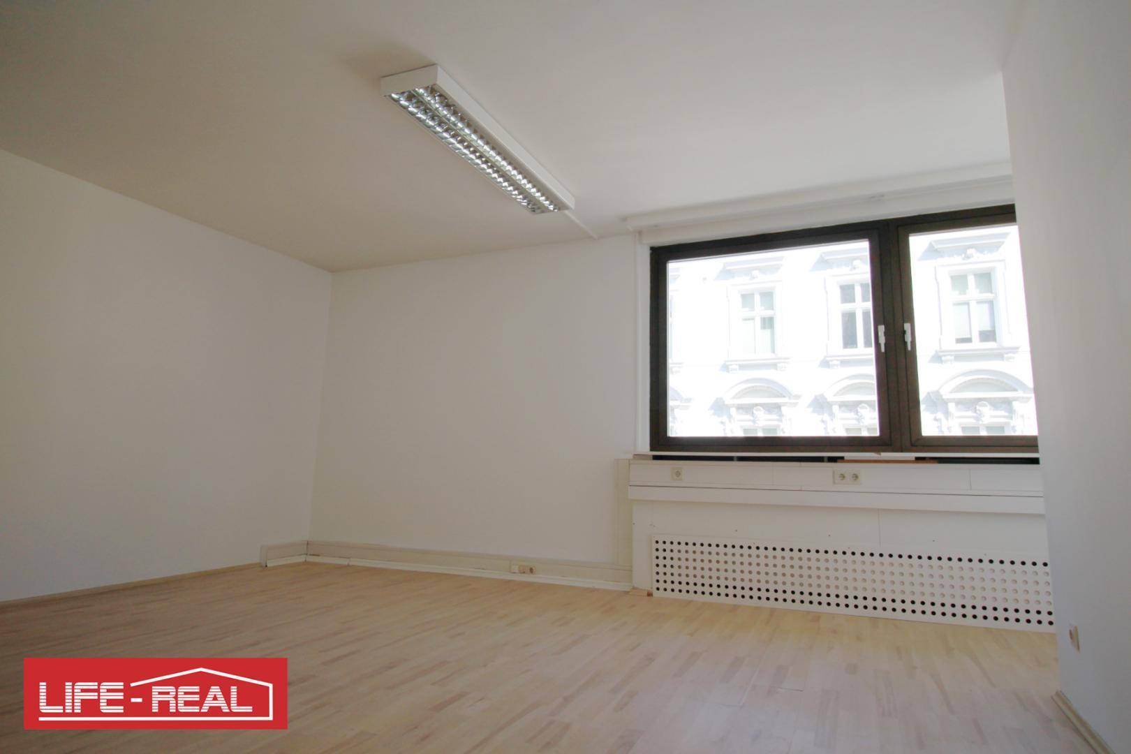 Heller Raum mit großen Fenstern und Holzfußboden, bietet eine angenehme Arbeitsatmosphäre.
