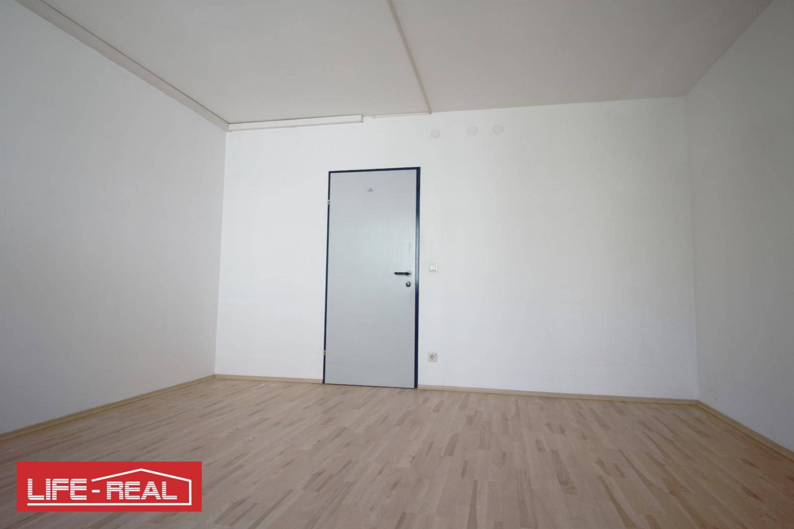 Schlichter, leerer Raum mit Holzfußboden und einer einfachen Tür, bereit zur Einrichtung.