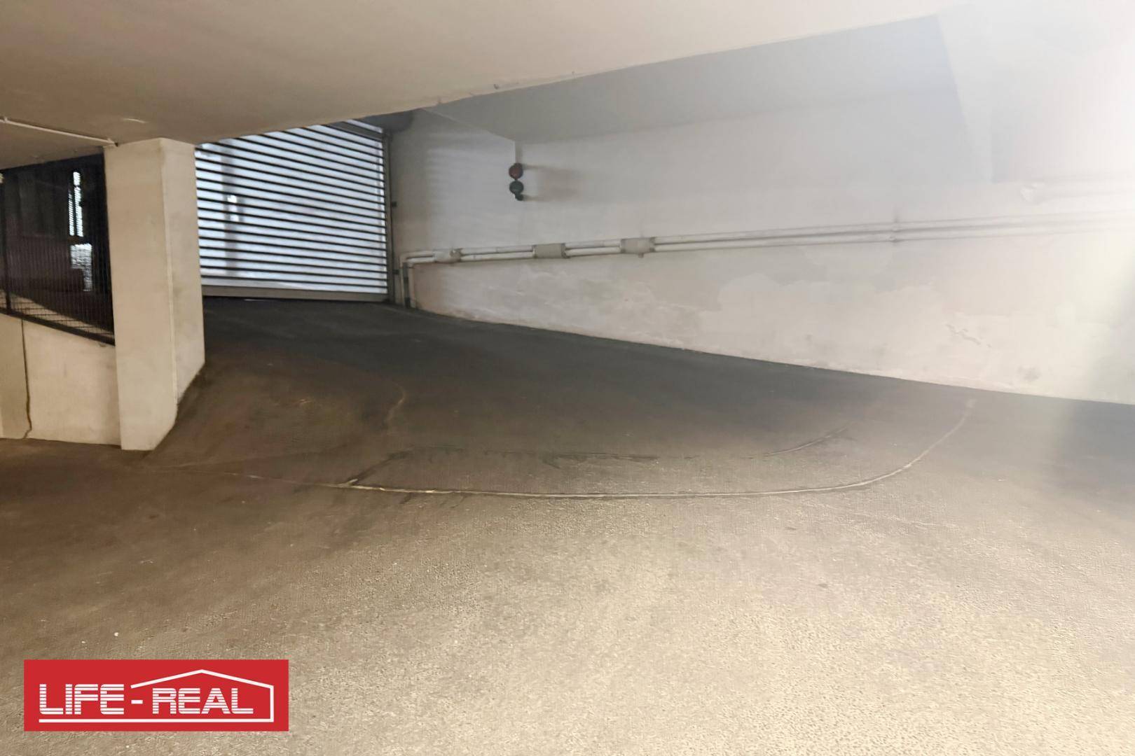 Einfahrt zu einer Tiefgarage mit einer Rampe, die in den unteren Bereich führt.