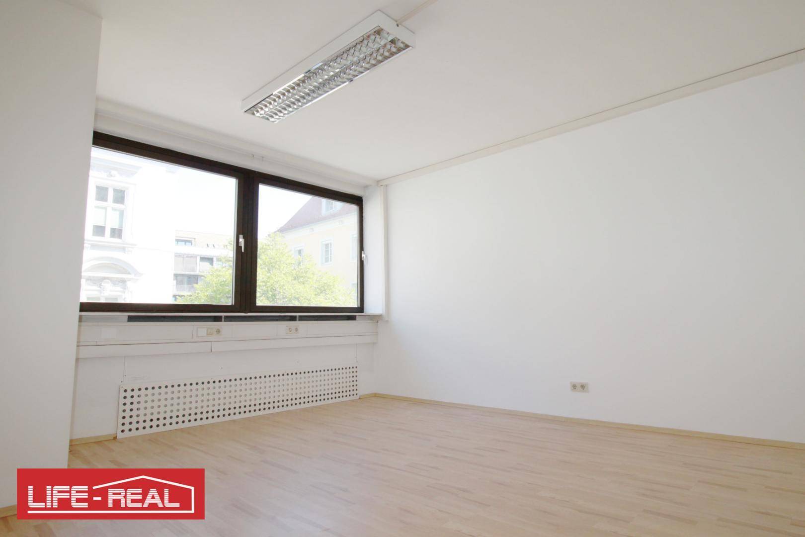 Heller Büroraum mit zwei großen Fenstern, die viel natürliches Licht in den Raum lassen.