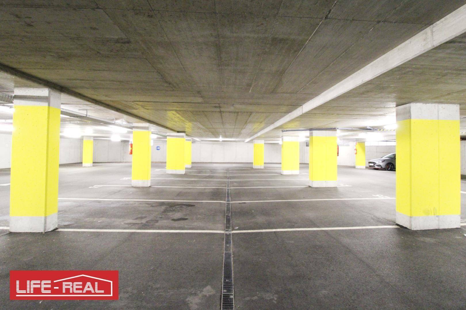 Helle Tiefgarage mit vielen Parkplätzen und klarer Bodenmarkierung.