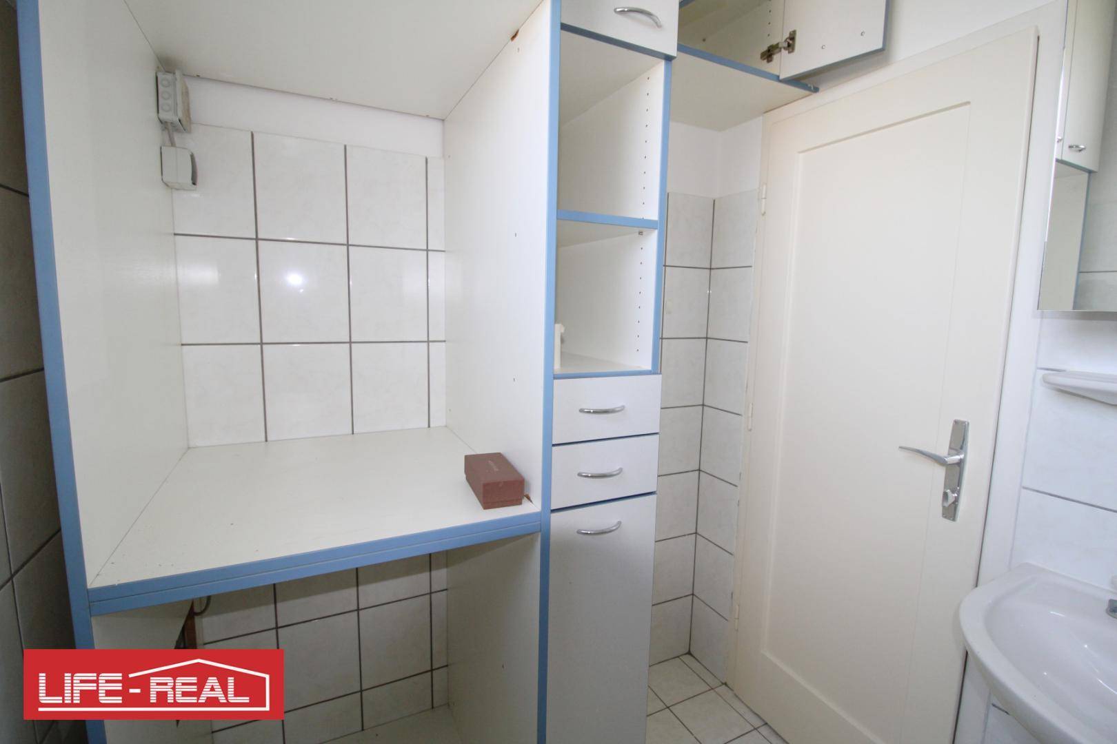 Badezimmer mit weißen Fliesen, Waschbecken und praktischen Einbauschränken.