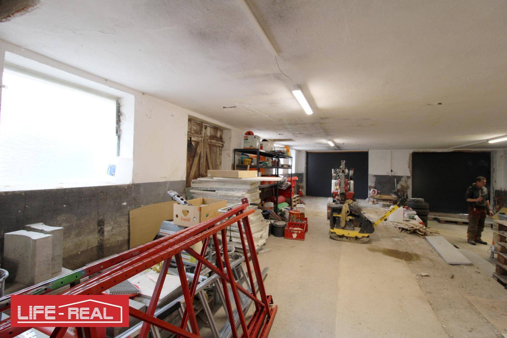Geräumiger Lagerbereich mit einem großen Fenster, das viel Tageslicht hereinlässt, und gelagerten Materialien.