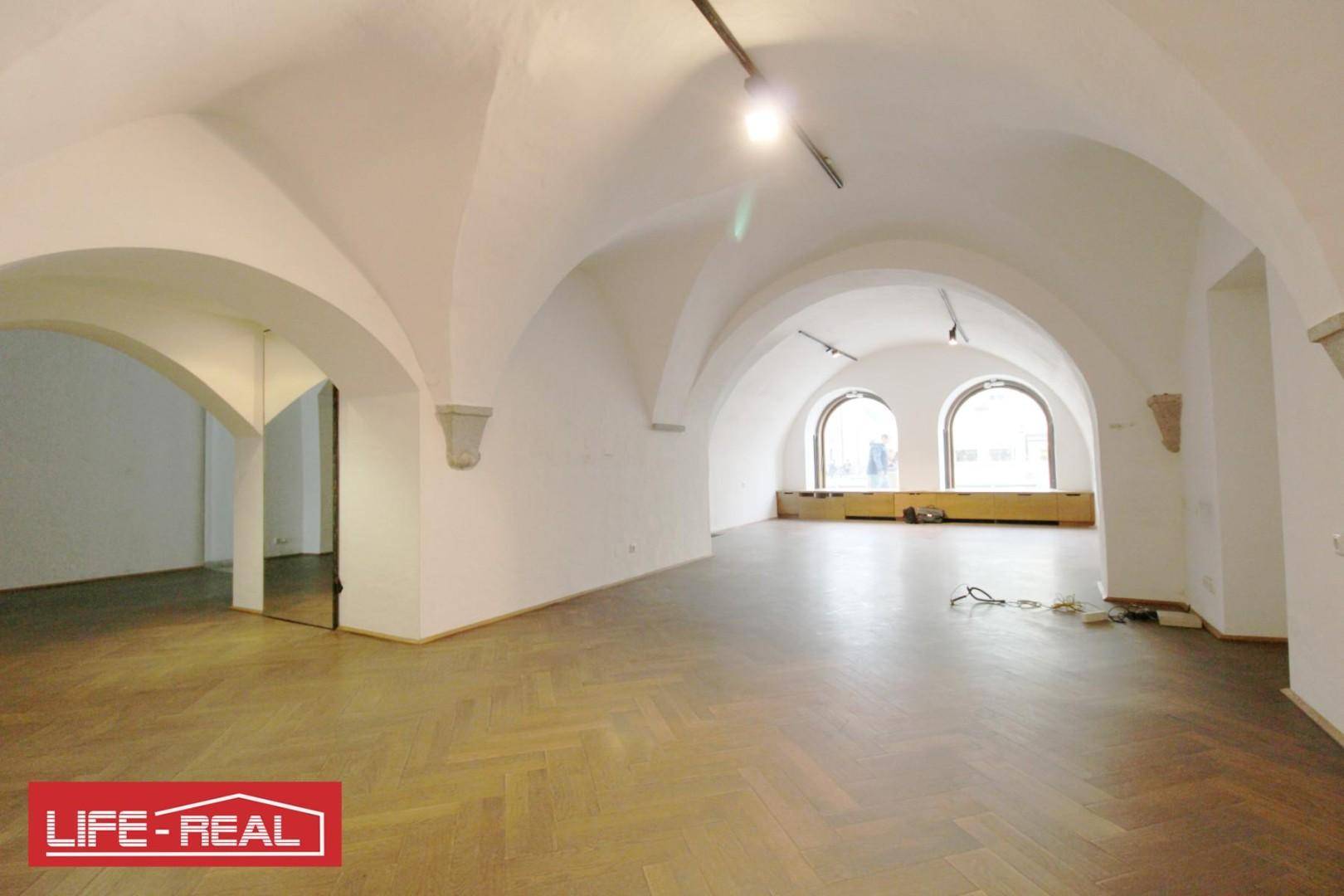 Weiter Blick in einen großen Raum mit markanten Gewölbedecken und elegantem Fischgrätparkett, ideal für vielseitige Nutzung.