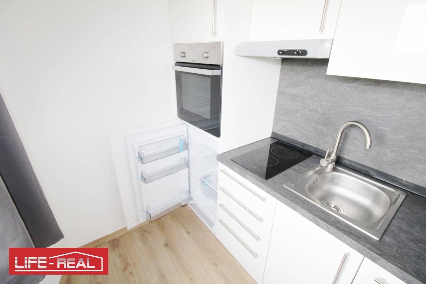 Kleine, moderne Küchenzeile mit Induktionskochfeld, Backofen und Kühlschrank.
