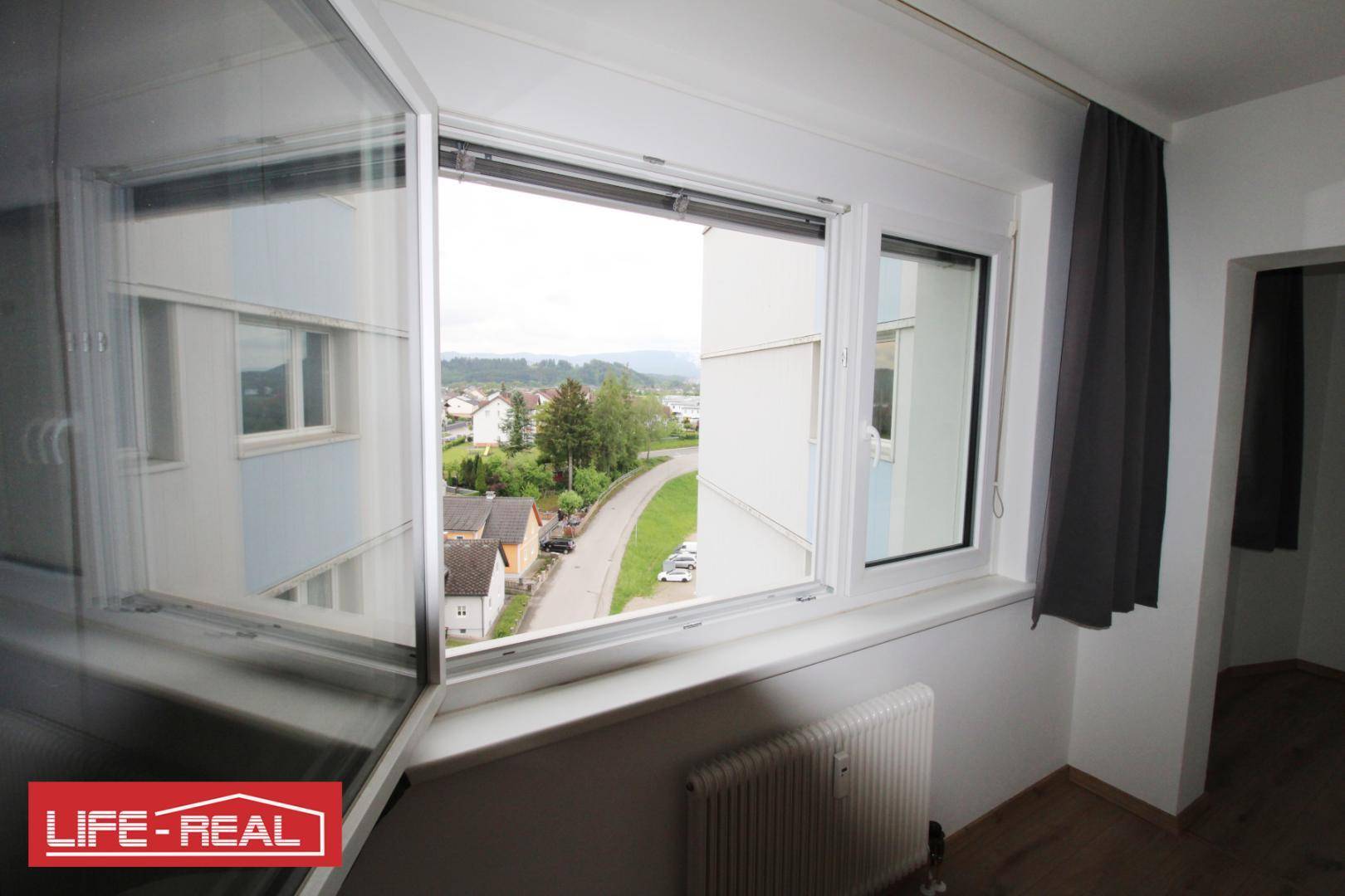 Fenster mit Ausblick auf die Straße und die umliegende Wohngegend.