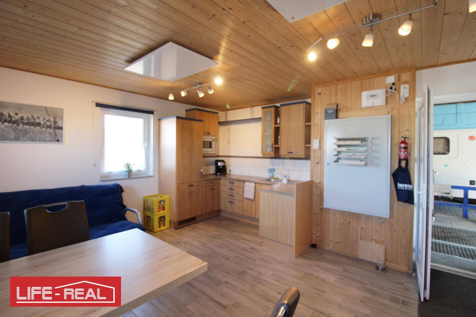 Kombinierter Küchen- und Essbereich mit Holzverkleidung an Wänden und Decke sowie hellen Holzschränken.