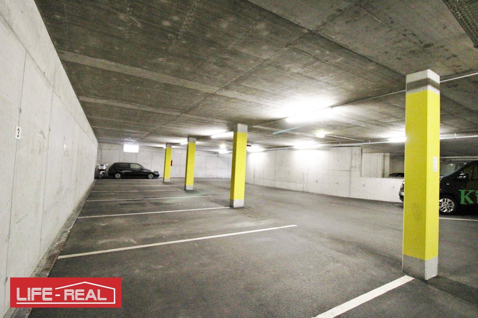 Geräumige Tiefgarage mit markierten Parkplätzen, gelben Säulen und Betonwänden, bietet ausreichend Stellfläche.