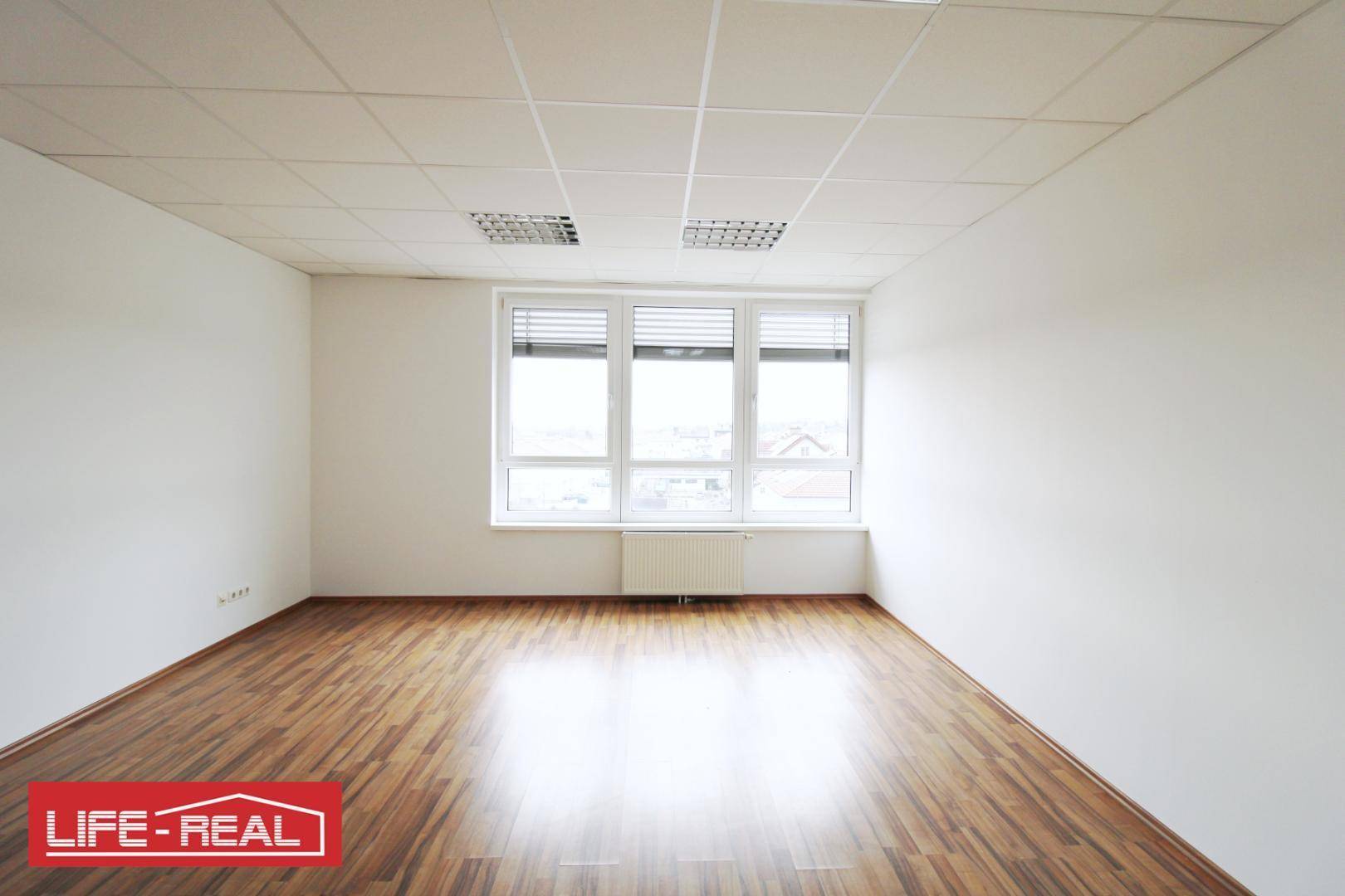 Helles Büro mit großen Fenstern, die viel Tageslicht hereinlassen, und einem Heizkörper darunter, ideal für Arbeitsplätze.