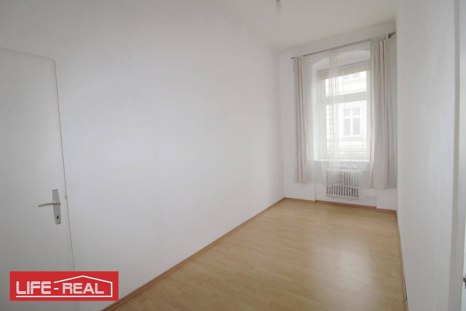 Freundliches Zimmer mit hellem Laminatboden und Fenster, geeignet als Schlafzimmer oder Kinderzimmer.