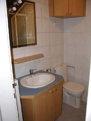 Kleines Badezimmer mit Waschbecken, Toilette und weißen Fliesen an den Wänden.