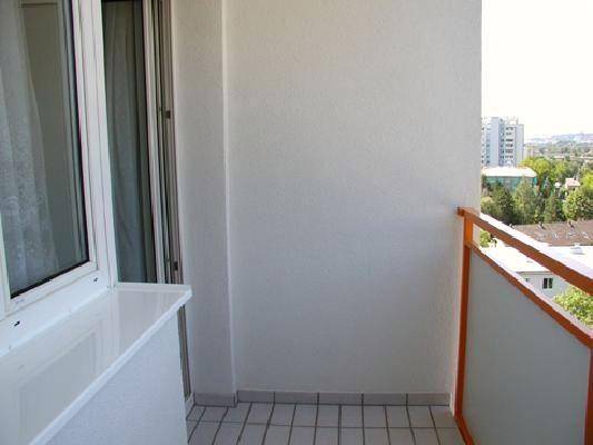Kleiner Balkon mit Fliesenboden und Blick auf die Stadt in der Ferne.