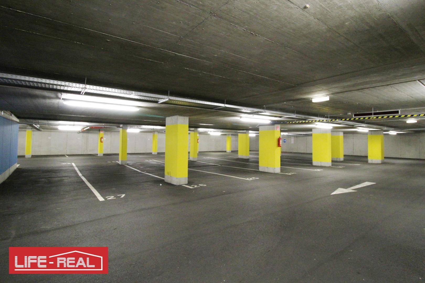 Geräumige Tiefgarage mit vielen Parkplätzen, Betonstruktur und guter Beleuchtung.