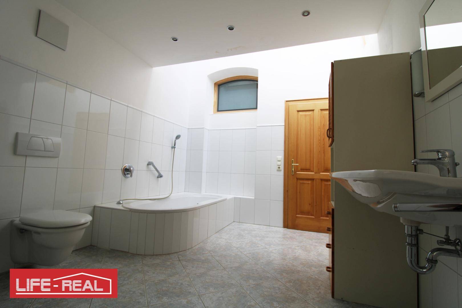 Geräumiges Badezimmer mit Badewanne, Waschbecken und WC, hell gefliest und funktional eingerichtet.
