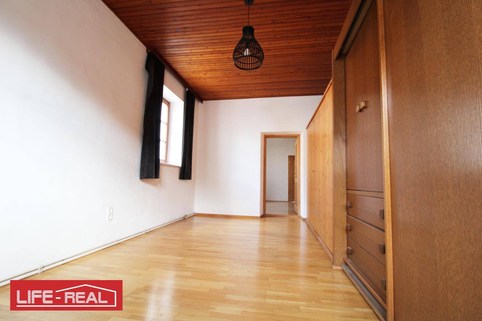Geräumiges Zimmer mit Holzbalkendecke und Parkettboden, bietet viel Platz und integrierten Stauraum.