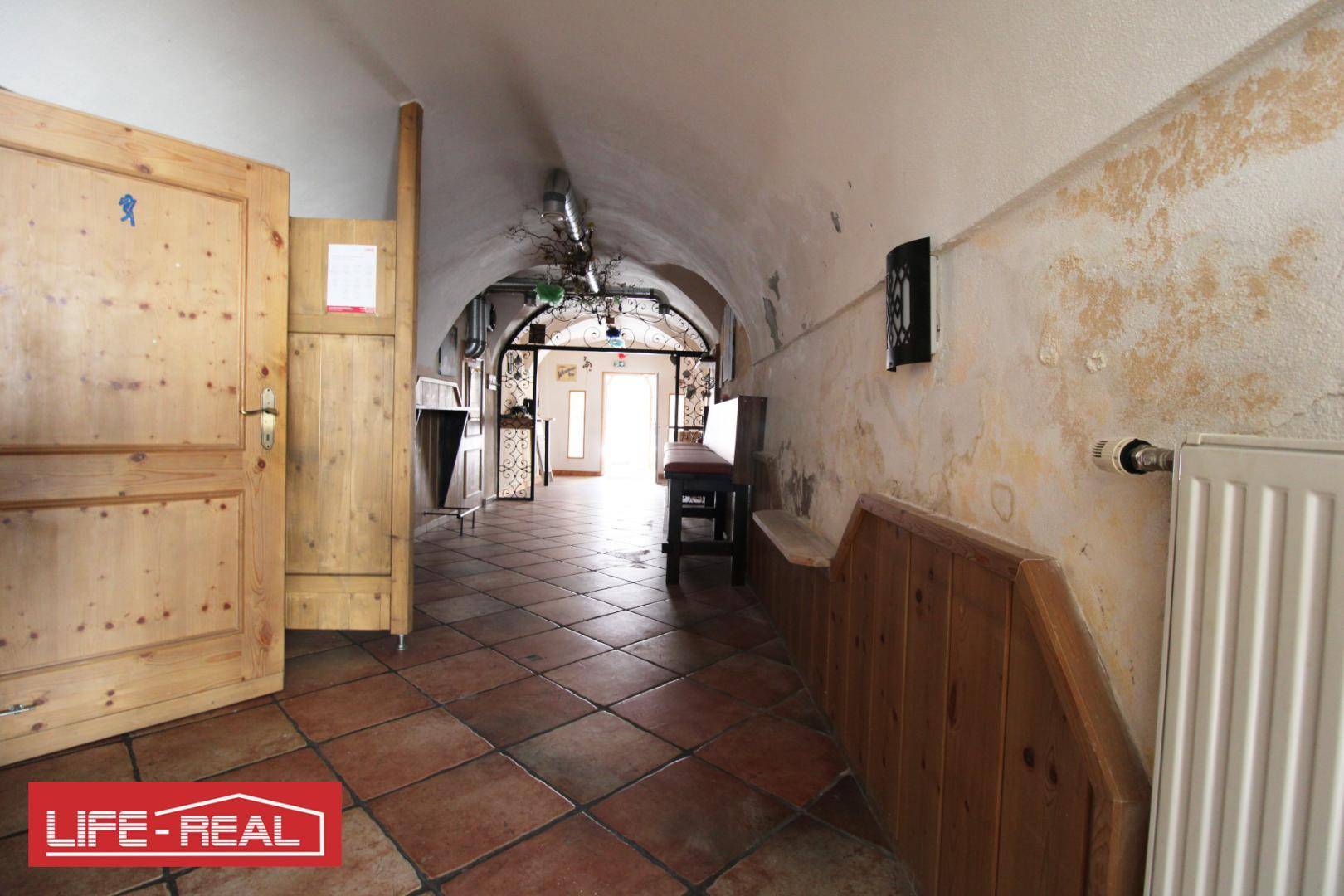 Historischer Flur mit Gewölbedecke, Holztüren und einem Heizkörper an der Wand.