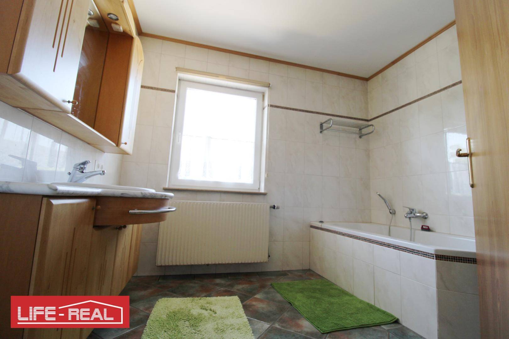 Badezimmer mit Badewanne, Waschbecken und Fenster.