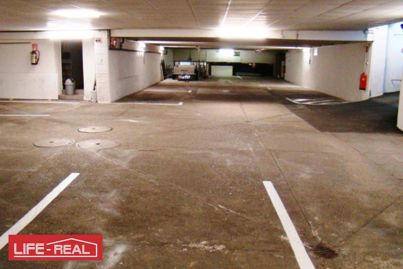 Geräumige Tiefgarage mit mehreren Stellplätzen und Brandschutzvorrichtungen an den Wänden.