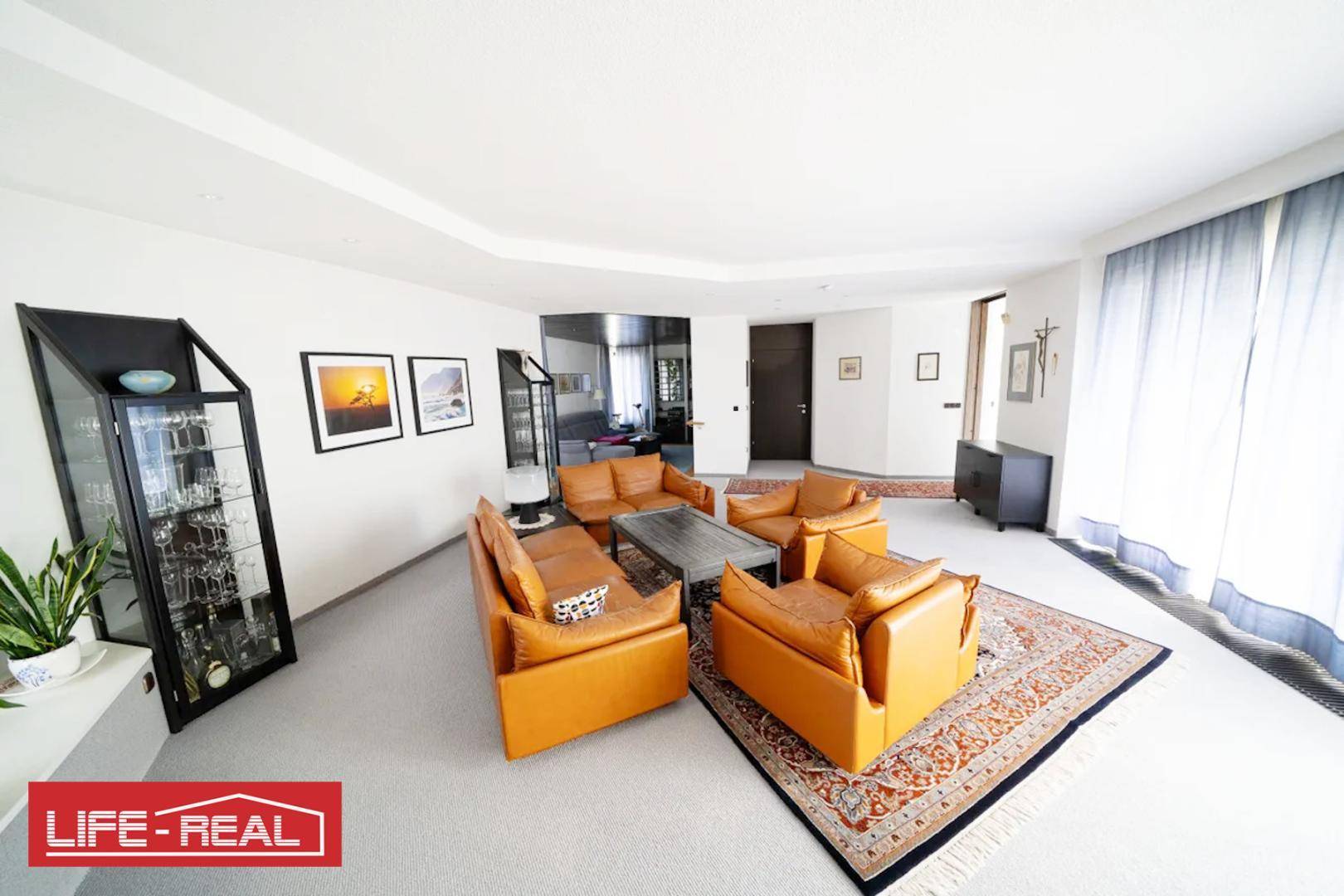 Großzügiges Wohnzimmer mit Ledersofas, Teppich und Blick auf den weiteren Wohnbereich.