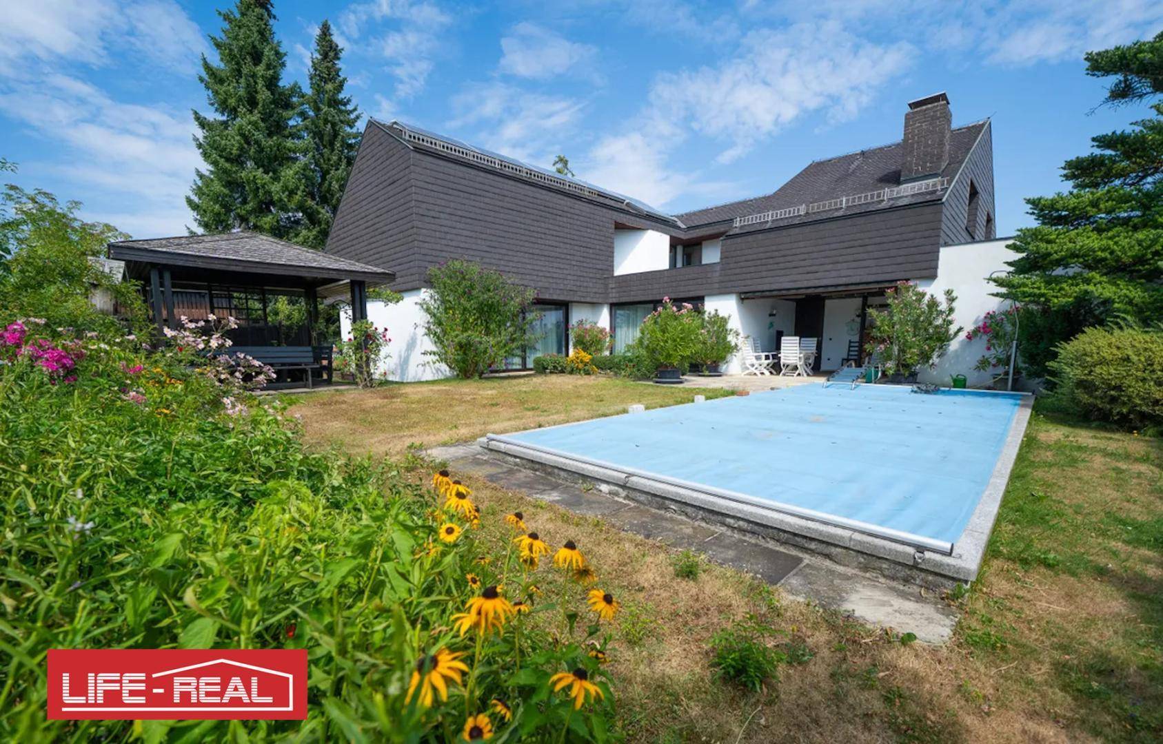 Weitläufiger Garten mit Pool, umgeben von blühenden Pflanzen und einem gemütlichen Pavillon.