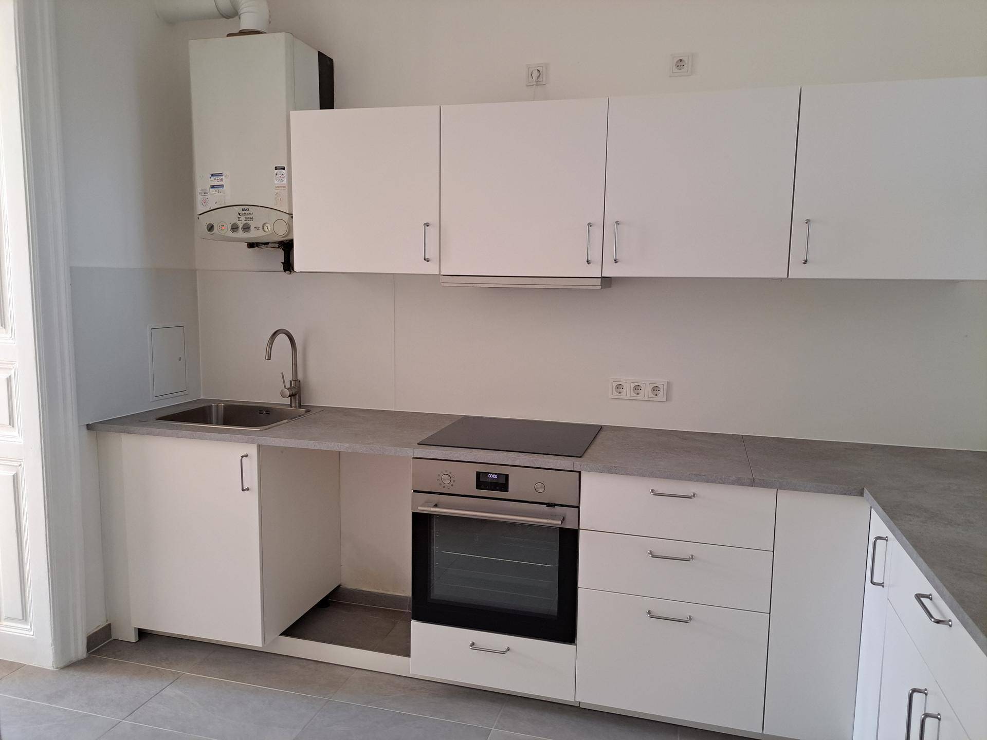 Neue Einbauküche mit weißen Schränken, Spüle, Kochfeld und Backofen, bereit zur Installation.