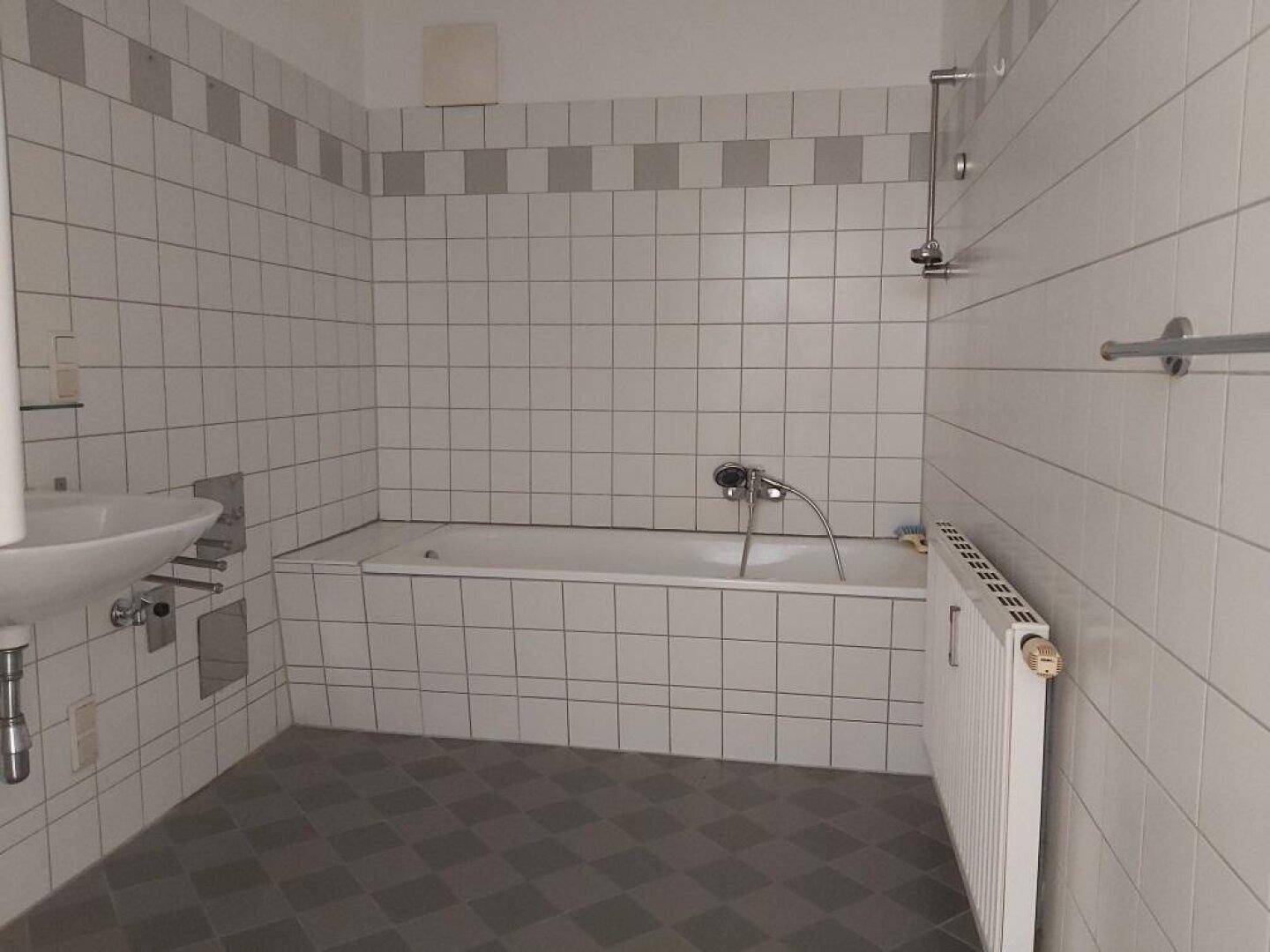 Badezimmer mit weiß gefliesten Wänden, Badewanne und Waschbecken.