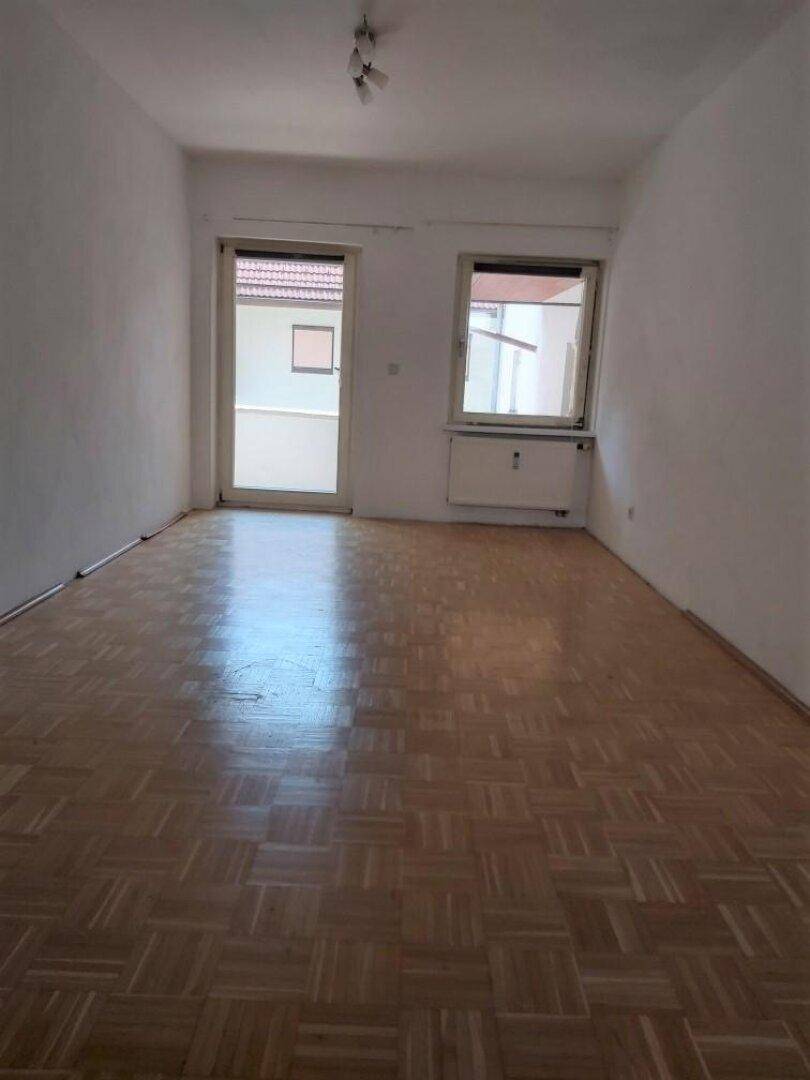 Geräumiges Zimmer mit Fischgrätparkett und Zugang zu einem Außenbereich.