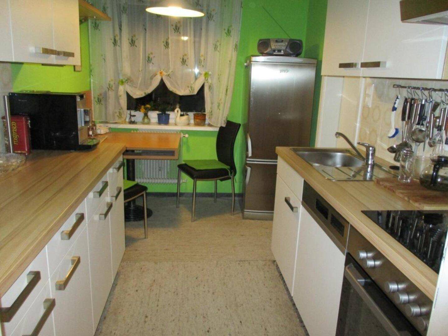 Helle Küche mit grünen Wänden, weißen Schränken und Holz-Arbeitsplatten.