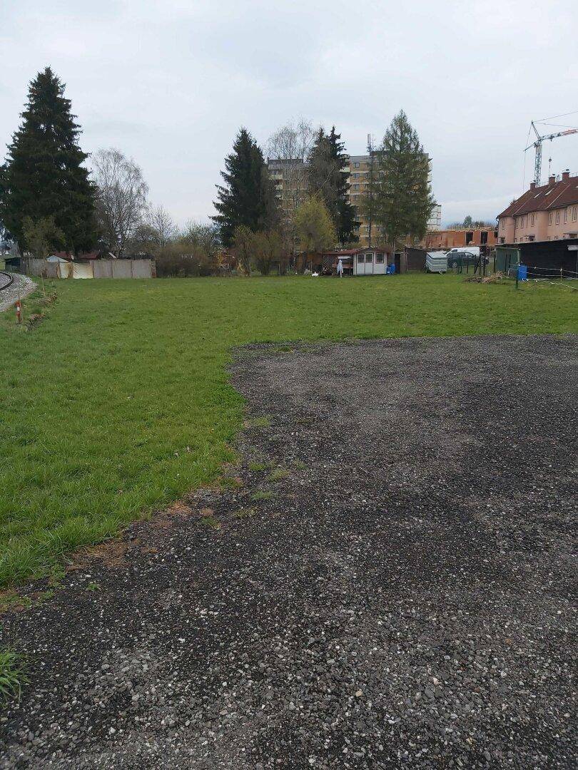 Grüne Wiese und Schotterfläche auf einem unbebauten Grundstück.