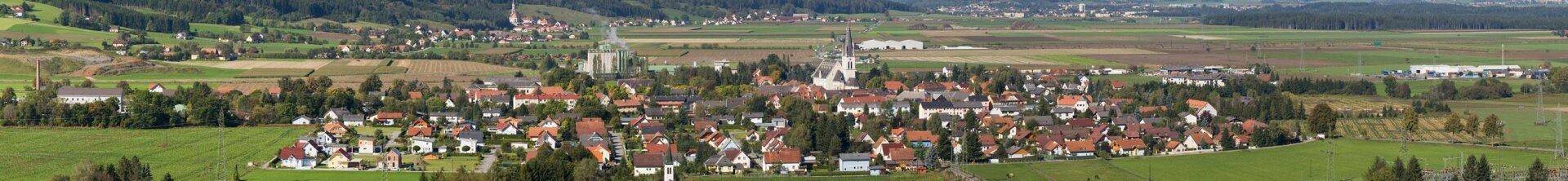 Panoramablick aus der Vogelperspektive auf eine ländliche Siedlung umgeben von grünen Feldern.